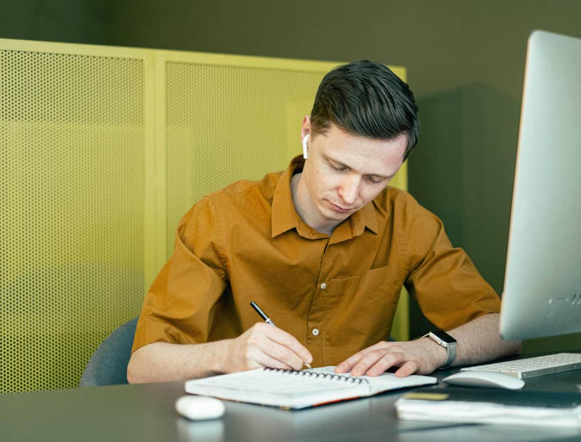 Registrar wearing an earphone writing admin tasks in a notebook as instructed by a senior staff over the phone