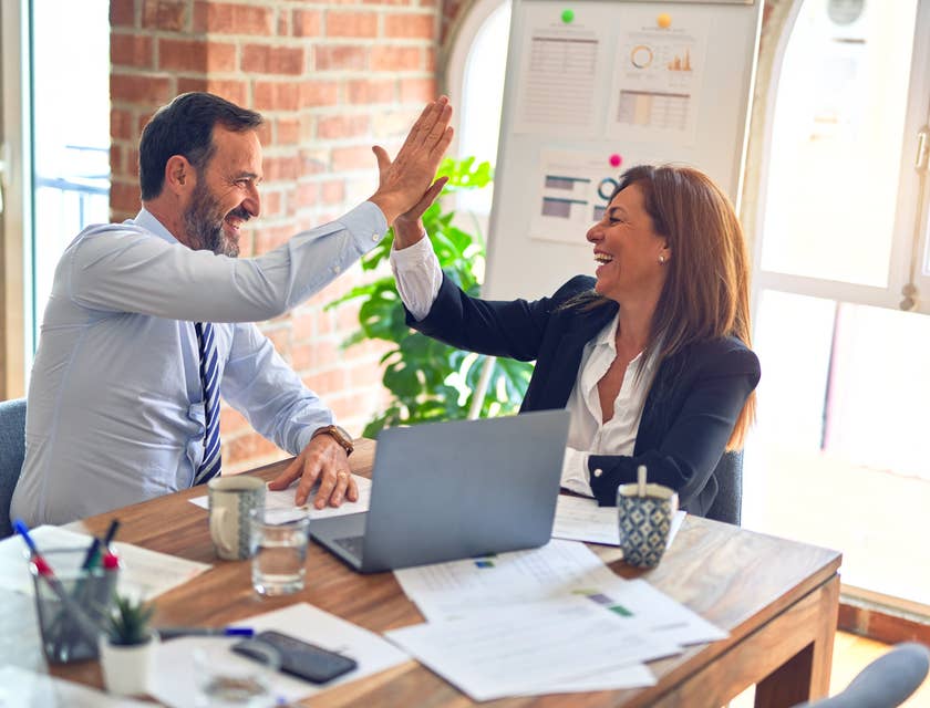 two relationship executives sitting in the office while smiling and giving high-five
