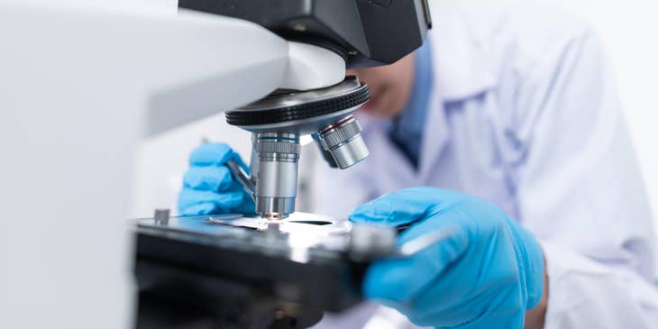 R&D engineer putting specimen on a microscope for research purposes