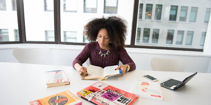Researcher reading several books to gather information on her research data