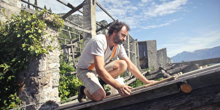Restoration technician focused on rebuilding the roof of a house on a sunny weather