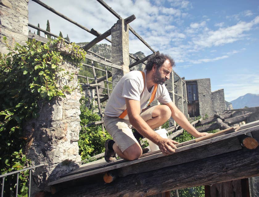 Restoration technician focused on rebuilding the roof of a house on a sunny weather