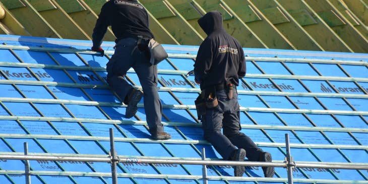 Roofers installing roof on a building.