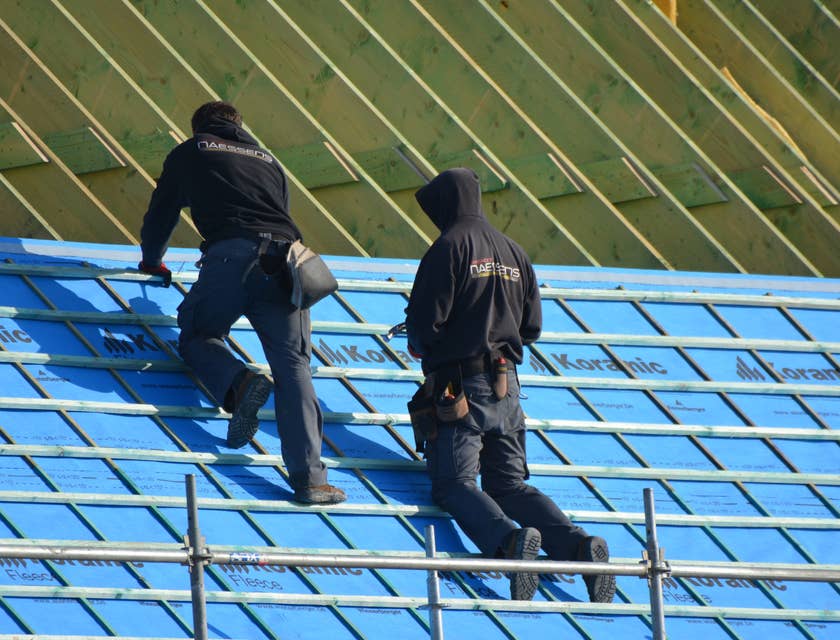 Roofers installing roof on a building.
