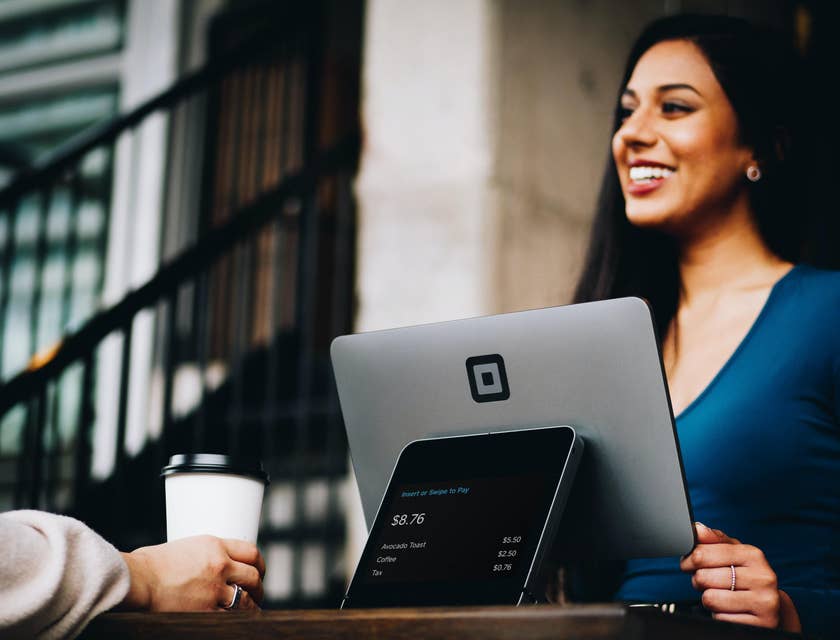Female sales associate serving a customer who is holding a coffee.