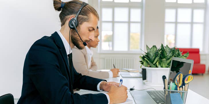 Sales coordinator inputting the orders of the customer on the computer and jotting it down for future references