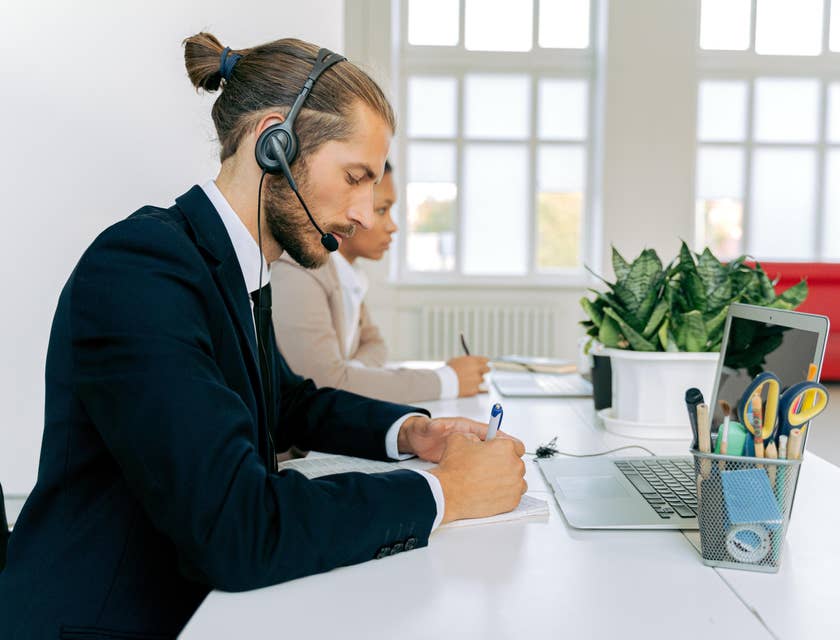 Sales coordinator inputting the orders of the customer on the computer and jotting it down for future references