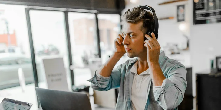 A salesforce administrator with headphones sitting behind a laptop.
