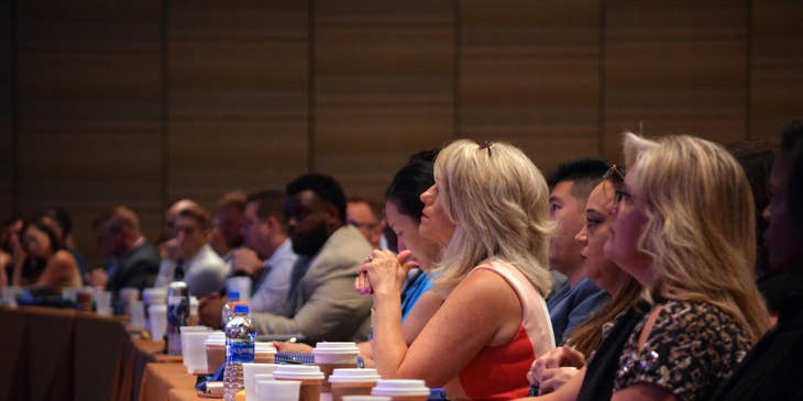 School administrator listens to a speaker about school updates in a conference room along with other teachers