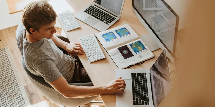 A man using three computers.
