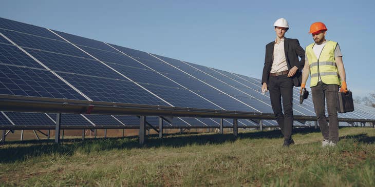 Senior architect visits solar panel design structure in a hard hat with an engineer