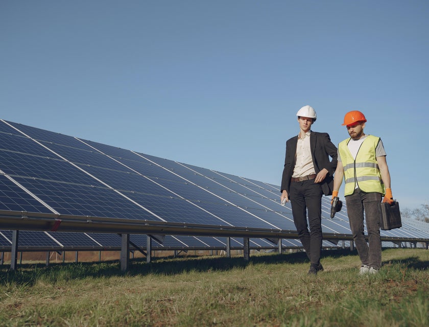 Senior architect visits solar panel design structure in a hard hat with an engineer