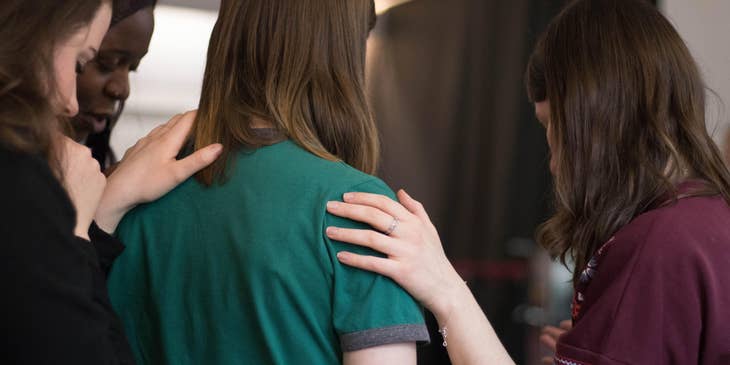 Service coordinator holding her client's shoulder and showing something to her while her support group looks on