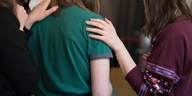 Service coordinator holding her client's shoulder and showing something to her while her support group looks on
