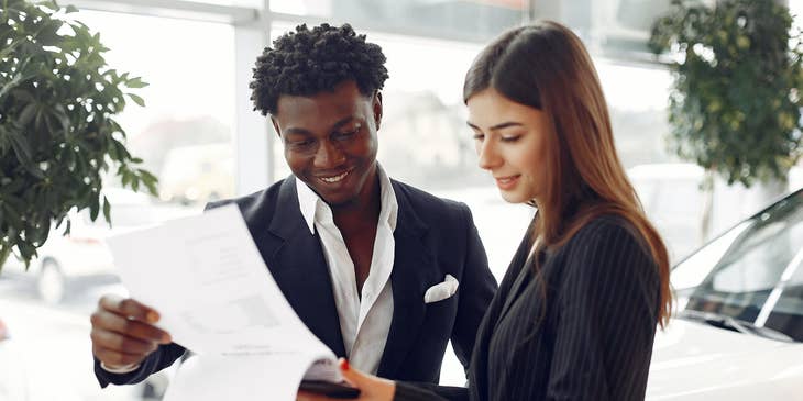 a service writer explaining the details written on paper to a male client while standing
