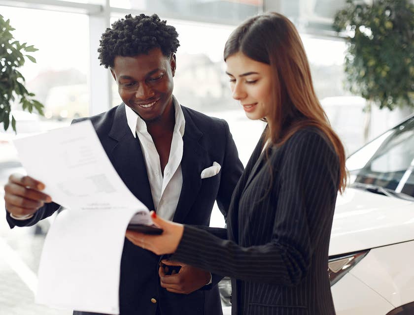 a service writer explaining the details written on paper to a male client while standing