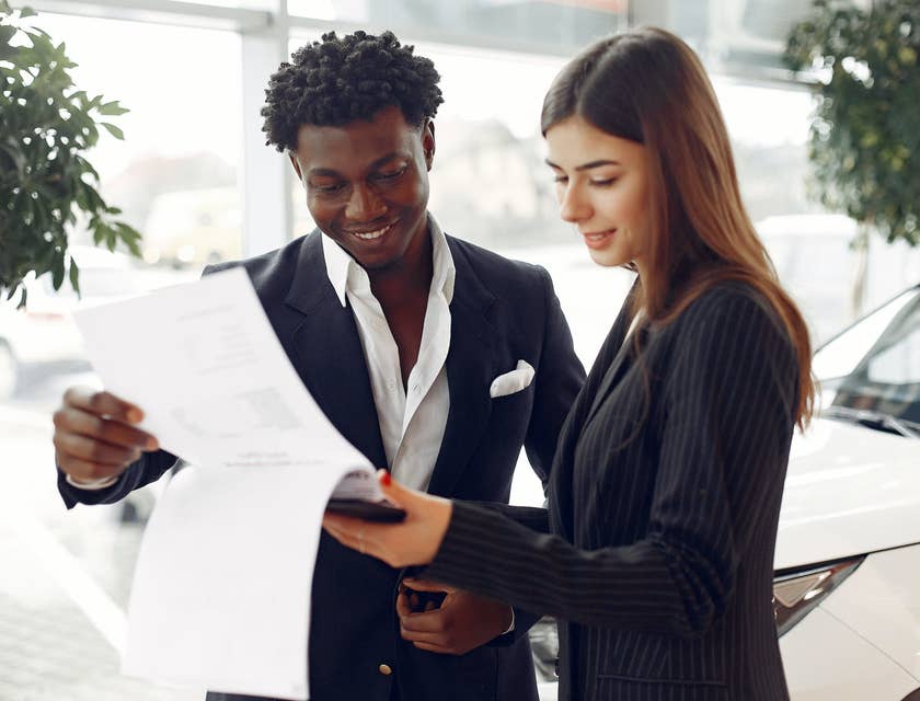 a service writer explaining the details written on paper to a male client while standing