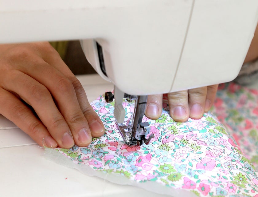 close up view of a sewing machine operator sewing a protective mask