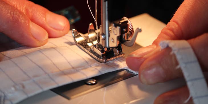 close up view of a sewing machine operator sewing a protective mask