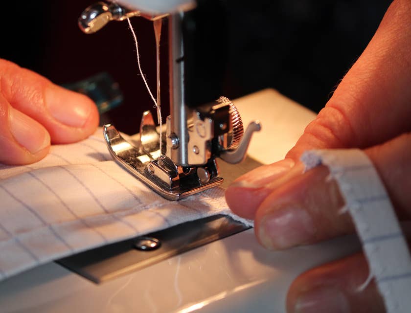 close up view of a sewing machine operator sewing a protective mask