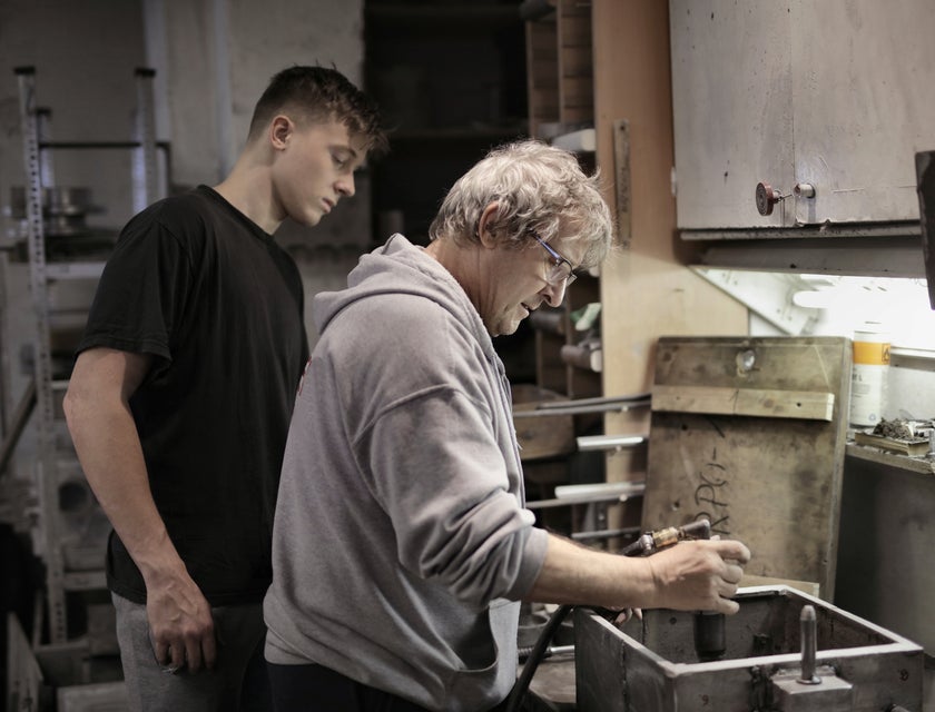 Shop foreman showing an apprentice how to operate the shop's machinery