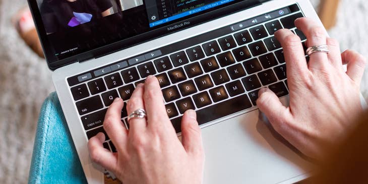 Software project manager works on a software program while on a video call with a client to discuss a new application