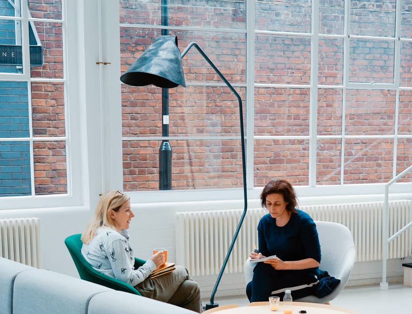 A Female Solicitor wearing light blue long sleeves holding an orange mug providing legal advice to a client.