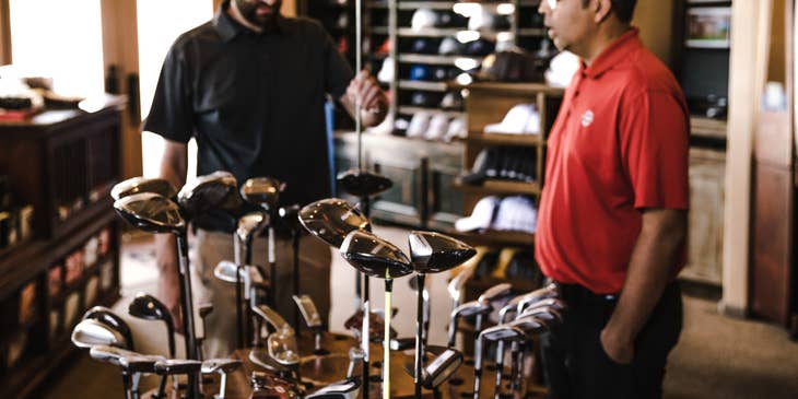 Sports administrator checking out new golf clubs to purchased for the club
