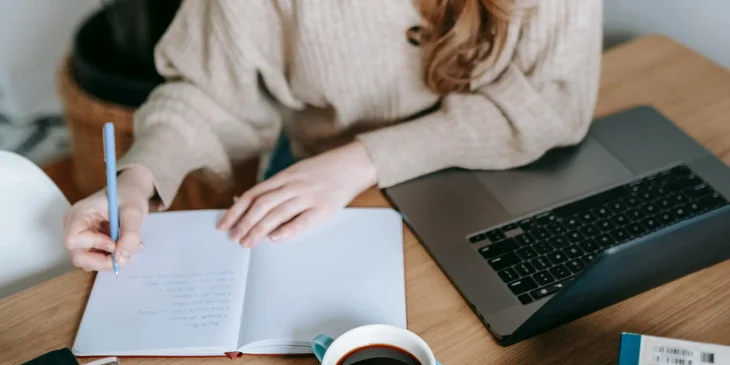 A staff accountant works on a journal entry for a monthly report while having a coffee.