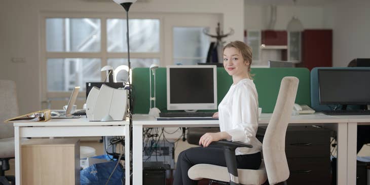 female staff assistant sitting on her workstation and getting ready to start her day at the office
