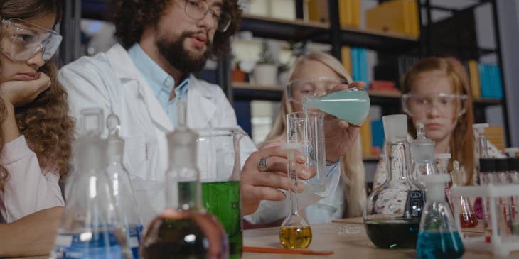 STEM teacher shows students how to transfer chemical solution to a flask