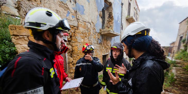Structural engineer discussing with his team the structural soundness of the building on site and wearing protective gears