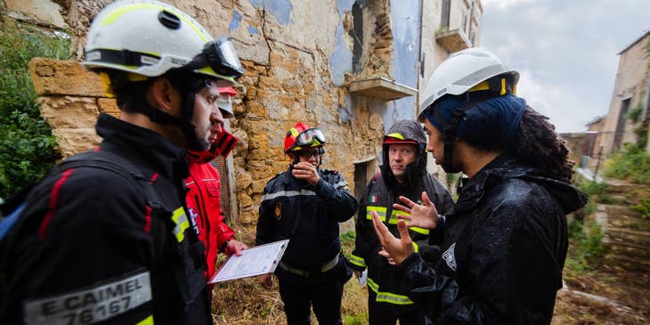 Structural Engineer discussing with his team the structural soundness of the building on site and wearing protective gears