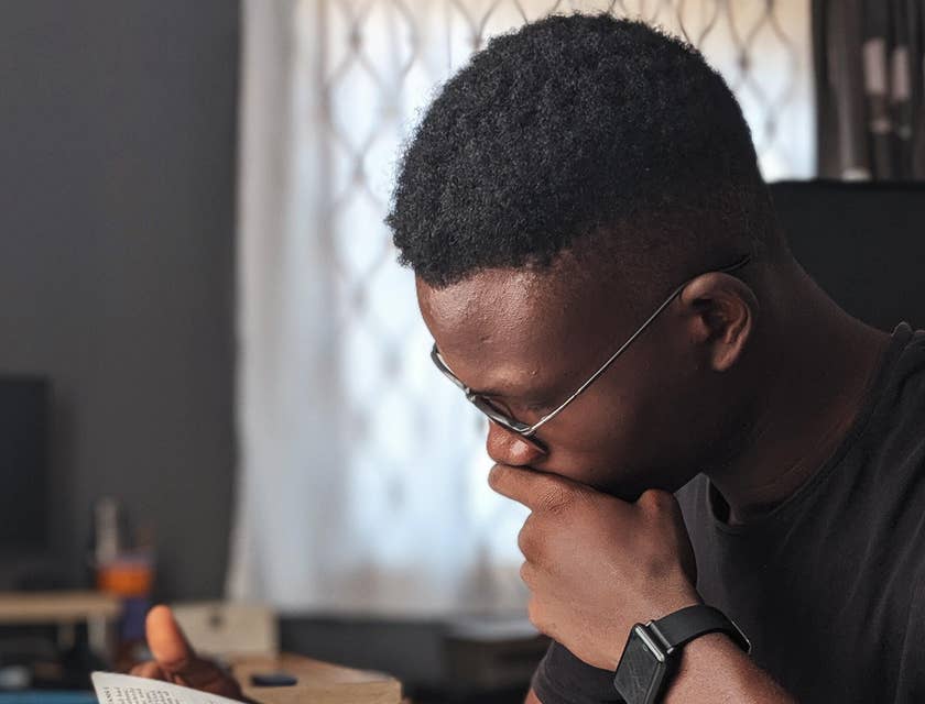 Student assistant reading a book and jotting down key parts to be used for a lecture
