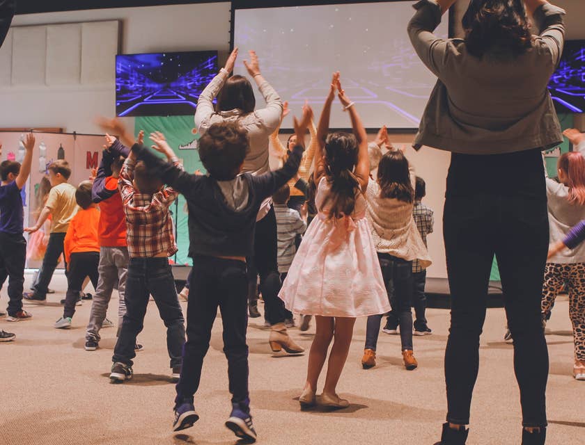 Sunday school teacher teaching students a dance of praise while viewing in a large screen
