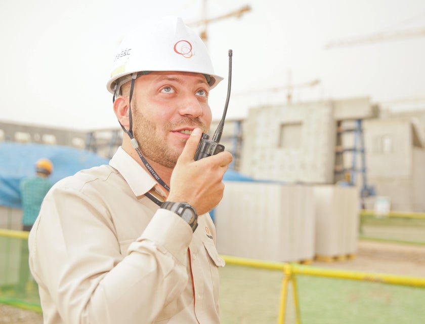Superintendent on a two way radio overseeing construction site.