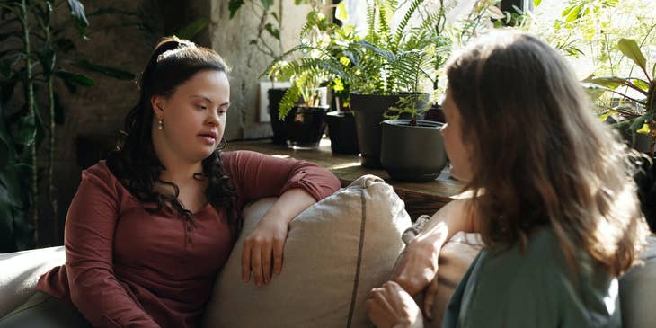 Support worker conversing casually with her client while sitting on the sofa