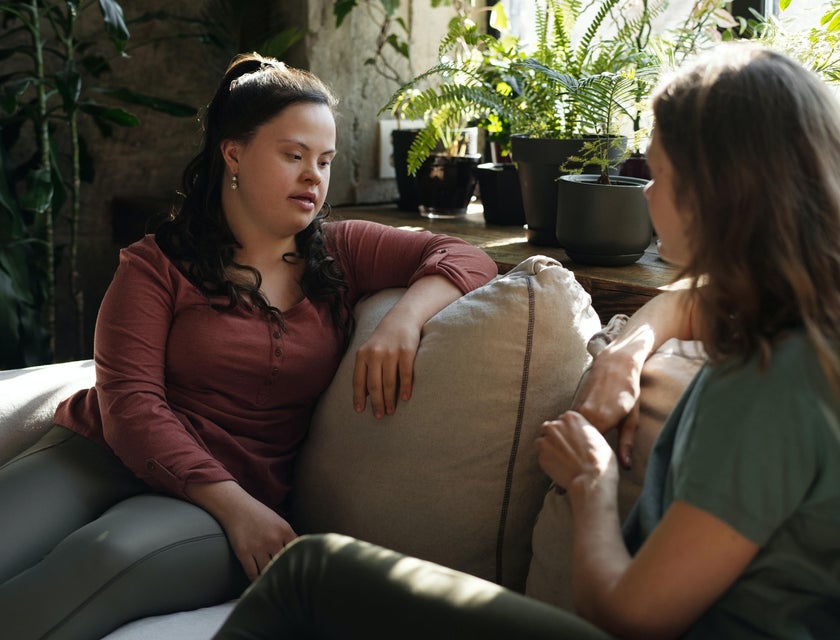 Support worker conversing casually with her client while sitting on the sofa