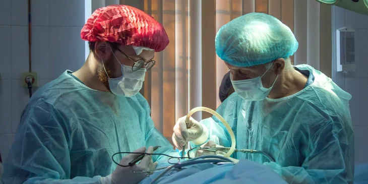 A surgical nurse holds a surgical equipment while assisting a surgeon during an operation.