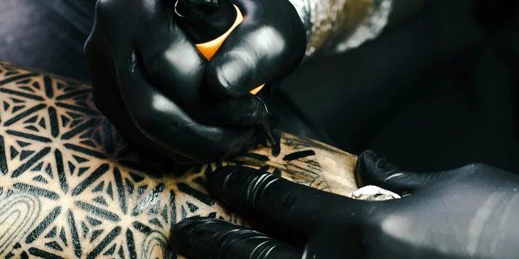 A tattoo artist working on an arm piece.
