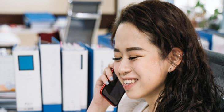 Tax accountant prepares a tax return report on a laptop while talking to someone on a mobile phone