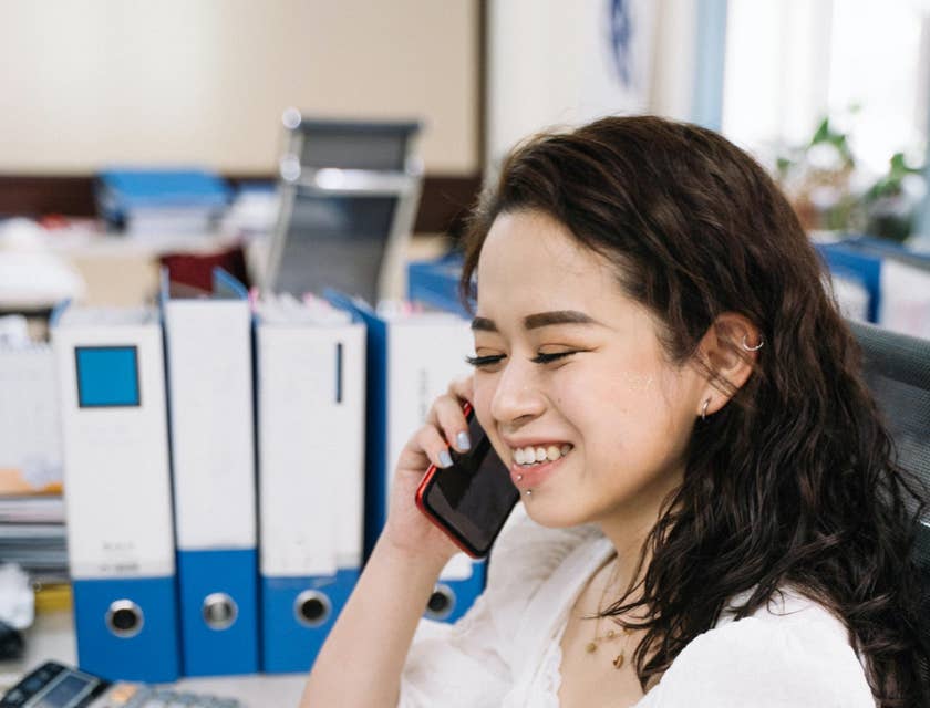 Tax accountant prepares a tax return report on a laptop while talking to someone on a mobile phone