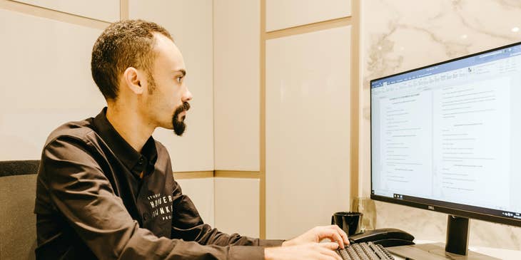Tax manager checking schedules in preparation for income tax audits on a computer in his office