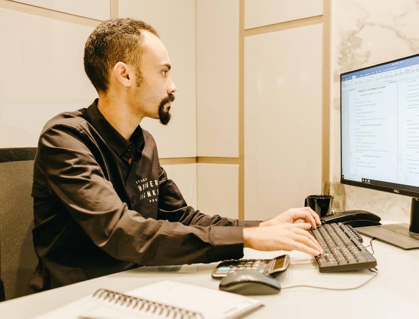 Tax manager checking schedules in preparation for income tax audits on a computer in his office
