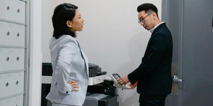 A technical assistant waiting for the documents to finish printing.