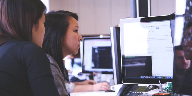 Technical consultant consults with management while resolving logged errors on the computer