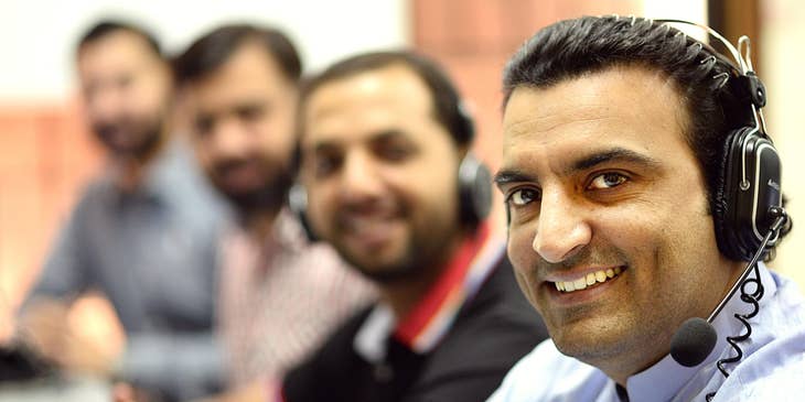 a team of telemarketers wearing headphones and smiling