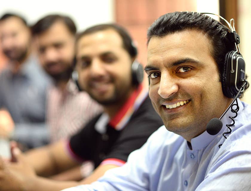 a team of telemarketers wearing headphones and smiling