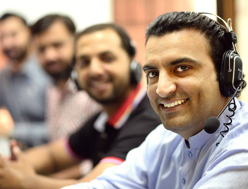 a team of Telemarketers wearing headphones and smiling