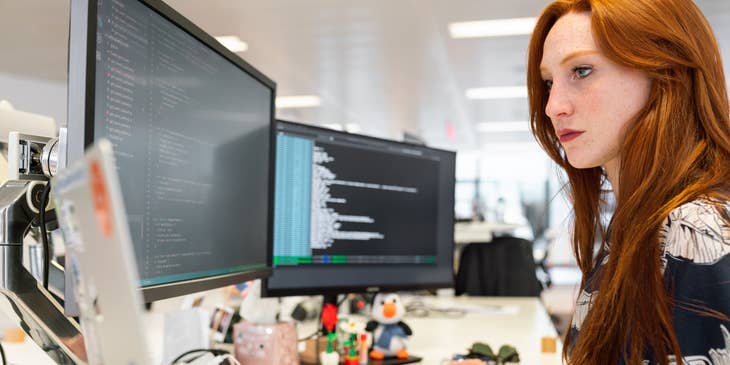 Test automation engineer developing an automation program on her workstation while sitting